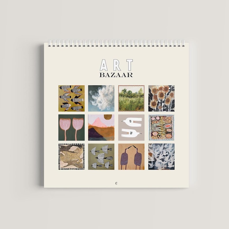 May include: A spiral-bound wall calendar with a cream-colored background featuring the text ART BAZAAR at the top. Below the text is a grid of twelve square illustrations depicting various subjects including birds, clouds, landscapes, and flowers.
