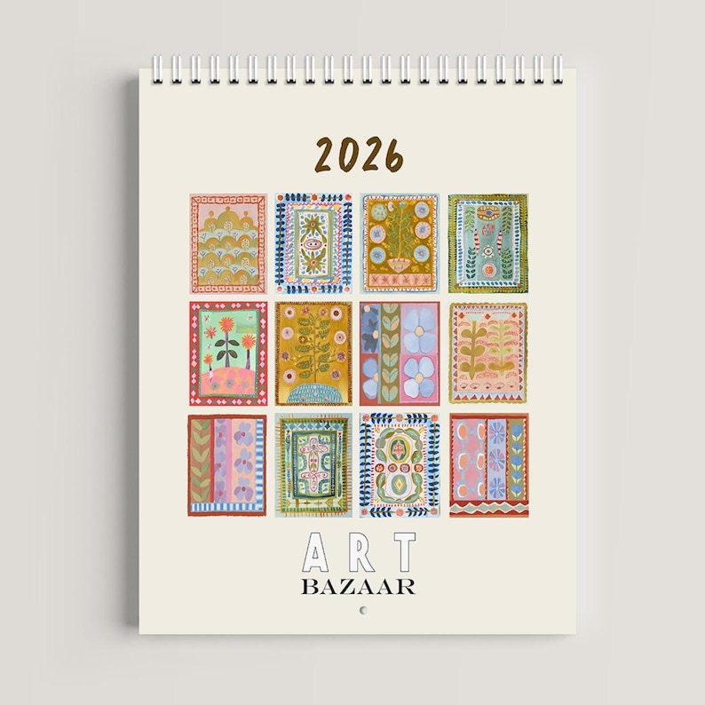 May include: A spiral-bound calendar for the year 2026, featuring twelve colorful, patterned illustrations. The calendar has the text "2026" at the top and "ART BAZAAR" at the bottom. The illustrations are in a variety of colors and designs.