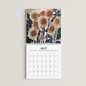 May include: A wall calendar for the month of April featuring a top section with an artistic illustration of sunflowers in shades of orange, brown, and black. The bottom section displays a grid for the month with the text April at the top.