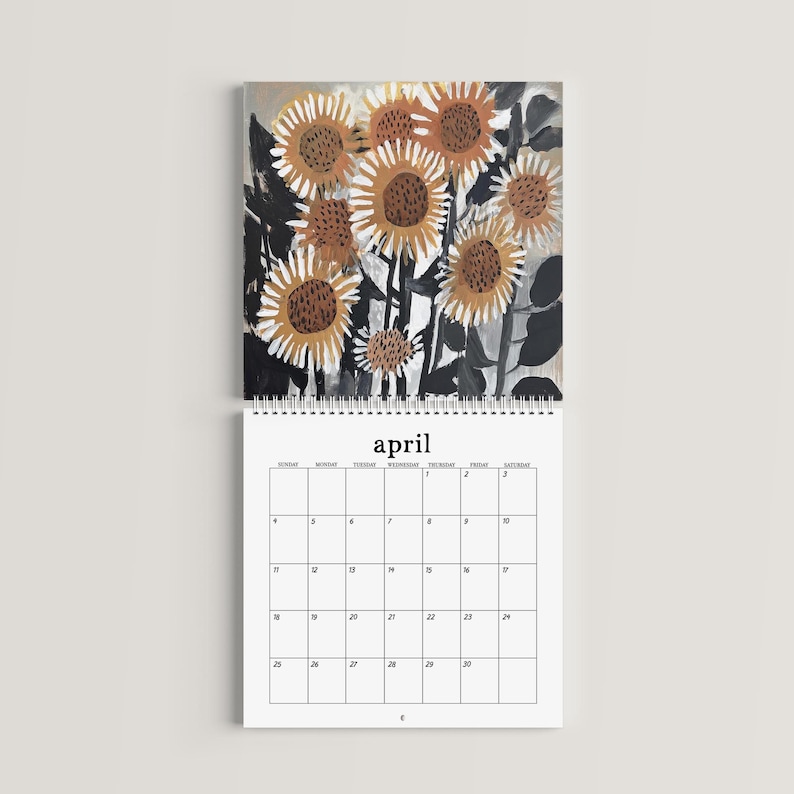 May include: A wall calendar for the month of April featuring a top section with an artistic illustration of sunflowers in shades of orange, brown, and black. The bottom section displays a grid for the month with the text April at the top.