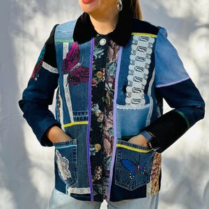 May include: A patchwork denim jacket with a black velvet collar and cuffs. The jacket features various denim patches, floral fabric, lace, and butterfly appliqués. It has two front pockets with yellow trim and a button closure.