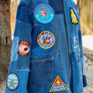 May include: A blue denim jacket with various patches sewn on. The patches include a US Customs Service patch, a Grey Bear's Fighting 201 patch, a WF Freising 19 Marathon 94 patch, an Aviation Challenge patch, and a patch with a helicopter and the text "MFG 3."