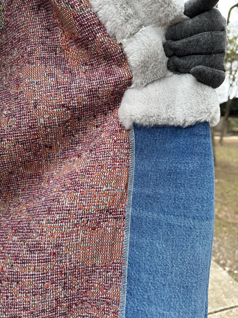 May include: Close-up of a jacket lining with a colorful woven fabric, a white faux fur trim, and a denim skirt.