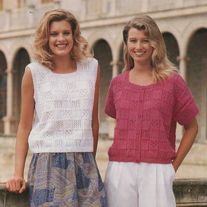 May include: Two women wearing knitted tops and shorts. One woman wears a white sleeveless top and a patterned skirt. The other wears a short-sleeved, button-up pink top and white shorts. The tops have a square pattern.
