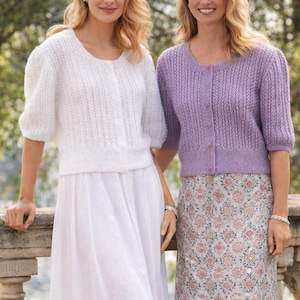 May include: A white ceramic mug with a black handle and the text "But First, Coffee" in a bold, black font. The mug is set against a blurred background, highlighting its clean design.