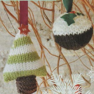 May include: Two knitted Christmas ornaments, one shaped like a Christmas tree with green and white stripes and the other shaped like a pudding with a brown and white design. Both ornaments have a red star on top.