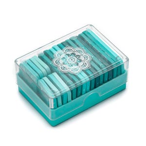 May include: A rectangular box with a clear lid, filled with teal and turquoise rectangular objects. The box has a teal base and a clear lid with a white mandala design. The objects inside are arranged in neat rows, creating a visually appealing pattern.
