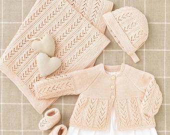 Puede incluir: Un conjunto de ropa de bebé de punto en color rosa pálido, que incluye un cárdigan, un gorro, botines y una manta. Todos los artículos están hechos con un delicado patrón de encaje.