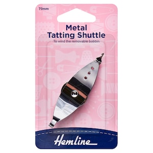 May include: A 70mm metal tatting shuttle on a pink and blue card. The silver shuttle has a pointed end and three small holes. The card features the text "Metal Tatting Shuttle" and "To wind the removable bobbin."