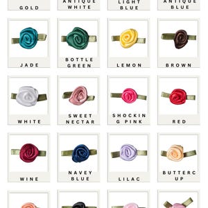 Op de afbeelding: Een raster van kleine stoffen rozenversieringen in verschillende kleuren, elk bevestigd aan een groen lint. Kleuren zijn goud, antiek wit, lichtblauw, antiek blauw, jade, flessegroen, citroen, bruin, zoete nectar, schokroze, rood, wijn, marineblauw, lila, boterbloem, donker perzik, zwart, zachtroze en roze.