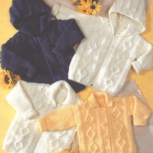 May include: Four knitted baby sweaters with different styles and colors. One is navy blue with a hood, one is white with a hood, one is white with a collar, and one is yellow with a collar.