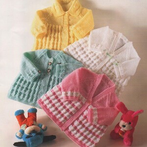 May include: Four knitted baby cardigans in different colors: yellow, green, white, and pink. The cardigans have button closures and are made with a textured stitch.