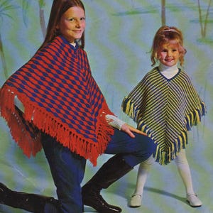 Könnte beinhalten: Zwei Kinder tragen bunte Strickponchos. Einer ist rot und blau mit Fransen, der andere gelb und blau mit Fransen. Sie tragen blaue Jeans, weiße Oberteile und schwarze Stiefel.