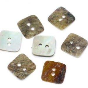 May include: A collection of seven square buttons with rounded corners, each featuring two central holes. The buttons display varied textures and colours, including shades of iridescent white, mottled brown, tan, and grey with natural patterns.