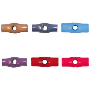 Puede incluir: Una colección de doce objetos de plástico en forma de T, cada uno con un agujero central. Los colores incluyen negro, gris, marrón, azul, morado, rojo, rosa, amarillo y blanco. Los objetos están espaciados sobre un fondo blanco.