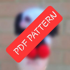 May include: A blurred image featuring a red rectangle with the text "PDF PATTERN" in white. The background is out of focus, with hints of a white and black object and two red spheres.