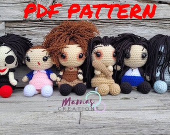 Può includere: Cinque bambole amigurumi all'uncinetto, ognuna con capelli e vestiti diversi. Le bambole sono sedute su una superficie di legno. Il testo "PDF PATTERN" è in alto nell'immagine.