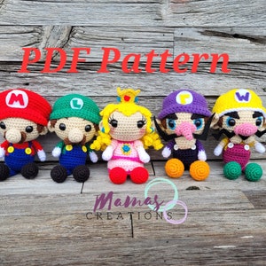 May include: Five crocheted plush toys of popular video game characters. The characters are Mario, Luigi, Peach, Wario, and Waluigi. The toys are all sitting on a wooden surface. The text "PDF Pattern" is written in red letters above the toys.