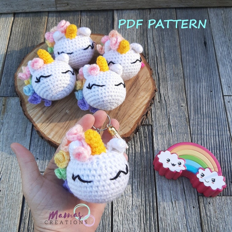 May include: A PDF pattern for crocheting a unicorn keychain. The pattern includes instructions for making a small, white unicorn with a rainbow mane and tail. The image shows four finished keychains and a rainbow-shaped toy.