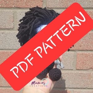 May include: A crochet amigurumi pattern for a black and gray character with a large afro. The pattern is available as a PDF download. The image shows the finished product, a small crocheted figure with a black afro, gray arms, and black legs.