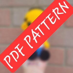 May include: A red banner with the text "PDF PATTERN" in white, angled across the image. The background is blurred, but appears to be a yellow and blue object. The background is a brick wall.