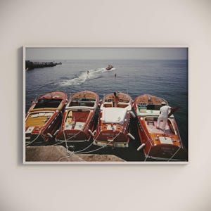 Peut inclure: Quatre bateaux à moteur en bois vintage amarrés à un quai. Les bateaux sont rouges et blancs avec des noms sur les côtés : "Sirocco", "Elves-El" et "Sunny-N-Myca".