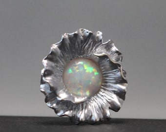 May include: A silver ring with a white opal gemstone set in a flower-shaped design.