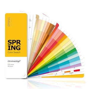 Op de afbeelding: Een waaier van kleurstalen met het label SPRING Color Swatch en de tekst chromawings 100 colors. All yours. De waaier bevat een breed scala aan individuele kaarten met diverse tinten, waaronder geel, oranje, rood, groen en blauw.