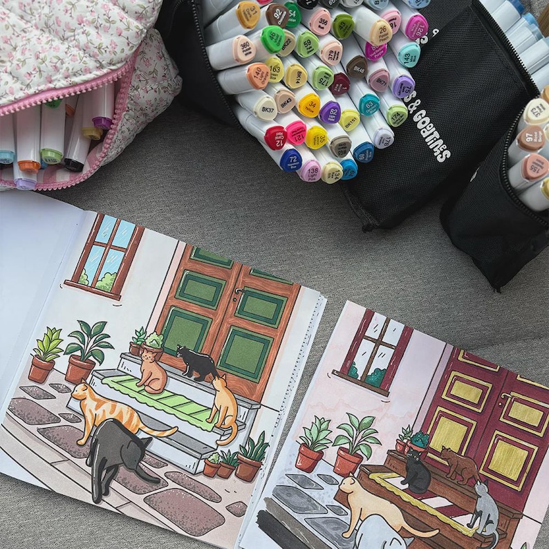 May include: An illustration of a house with cats on the porch, with markers and a floral pencil case in the background. The drawing depicts a house with a green door, potted plants, and cats in various poses. The markers are in black cases.