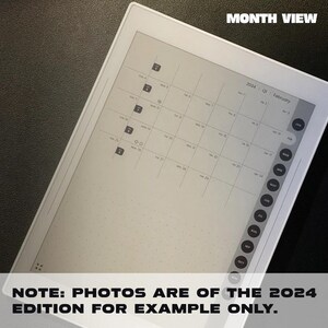 May include: A white e-reader with a monthly calendar view for the year 2024. The calendar is displayed on the screen, with the month of February highlighted. The screen is blank, except for the calendar and the text "MONTH VIEW" at the top.