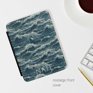 Puede incluir: Una funda rectangular para lector electrónico con una ilustración detallada de olas oceánicas turbulentas en tonos azul profundo, verde azulado y blanco. El nombre NATI está impreso en una fuente blanca sin remates cerca de la parte inferior.
