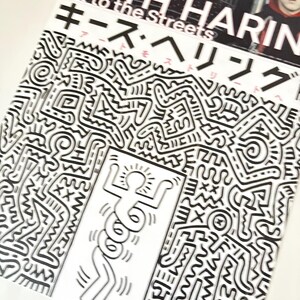 May include: A black and white book cover with the title "Keith Haring Art to the Streets" in white text. The cover features a black and white illustration of a stick figure dancing in a black and white abstract pattern.