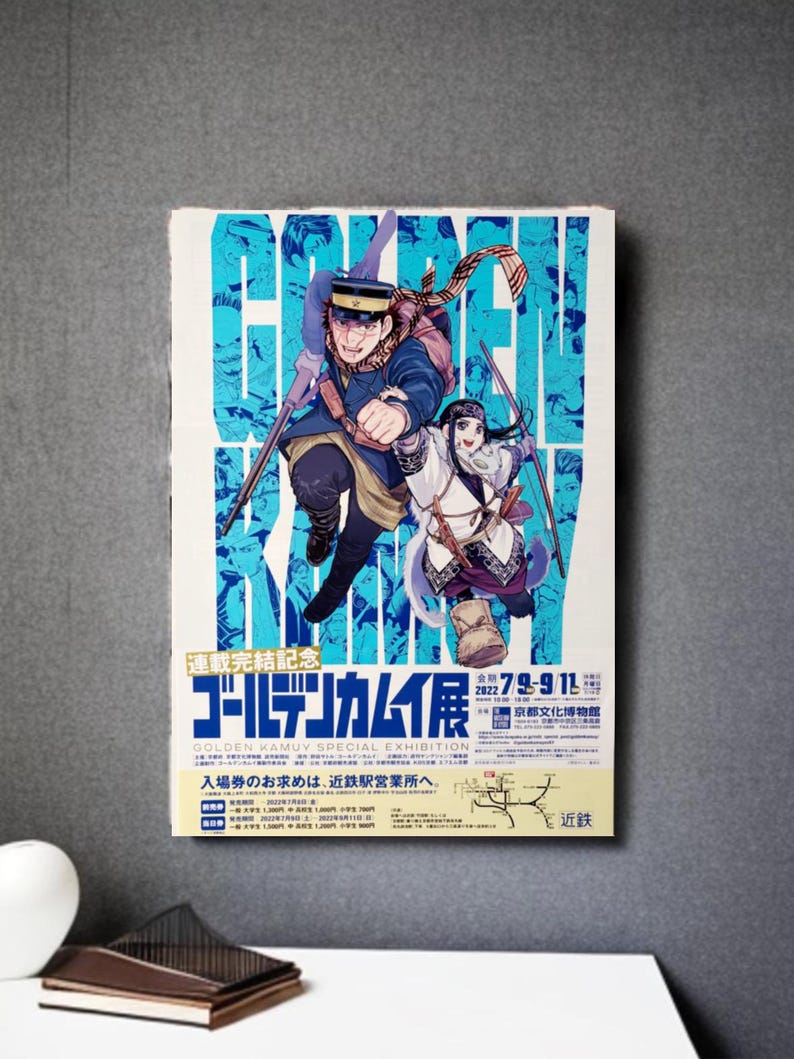 May include: A poster for the "Golden Kamuy Special Exhibition" with two illustrated characters holding weapons. The poster is blue and white, with Japanese text and the dates "7/9-9/11 2022".
