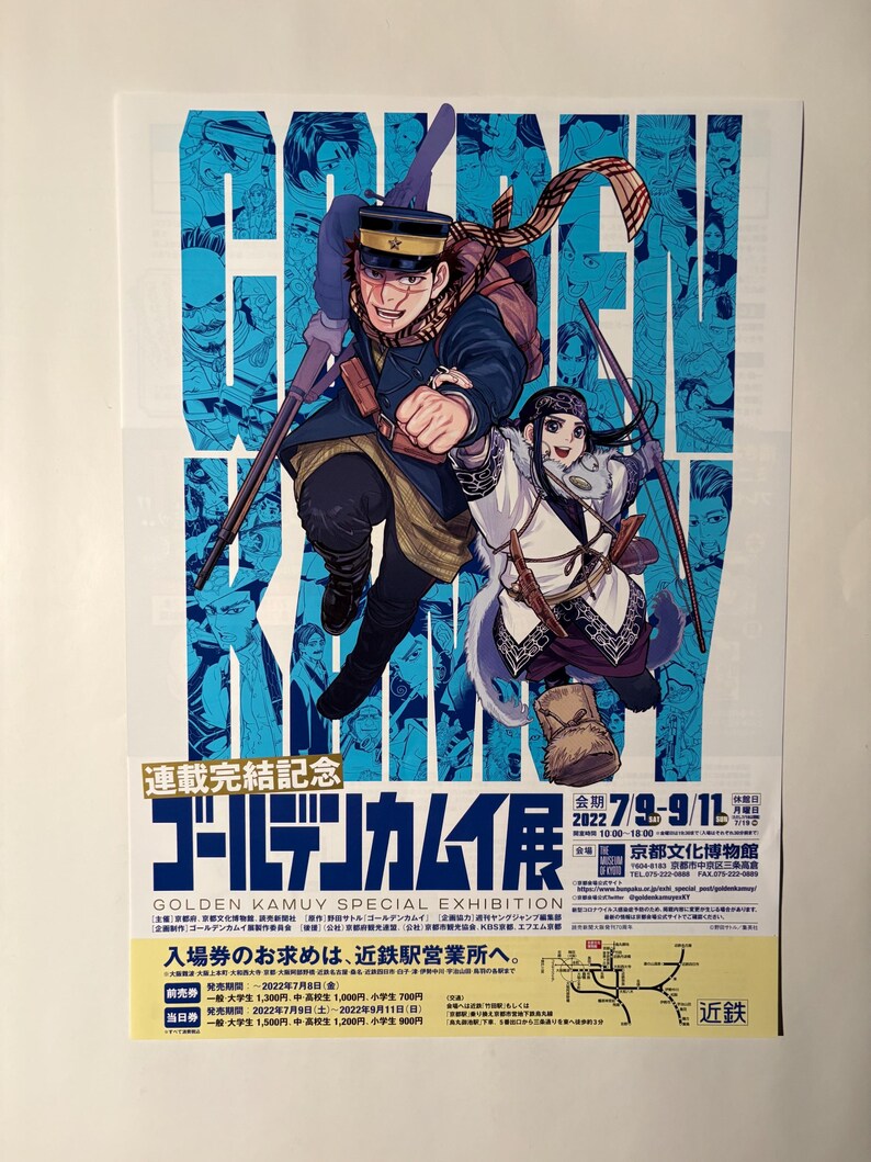 May include: A poster advertising the Golden Kamuy Special Exhibition, with two illustrated characters in dynamic poses. The background is light blue with character portraits. The poster includes Japanese text and exhibition details.