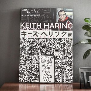 May include: A black and white poster with a graphic design of a person with a snake for a body. The poster is for a Keith Haring exhibit titled "Art to the Streets". The poster also includes the text "Keith Haring" and "Art to the Streets" in large, bold letters. The poster is in Japanese and English.