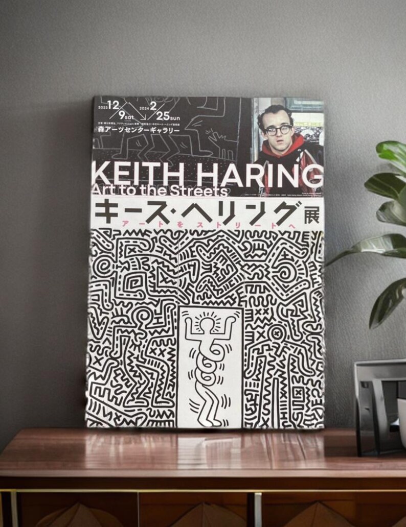 May include: A black and white poster with a graphic design of a person with a snake for a body. The poster is for a Keith Haring exhibit titled "Art to the Streets". The poster also includes the text "Keith Haring" and "Art to the Streets" in large, bold letters. The poster is in Japanese and English.
