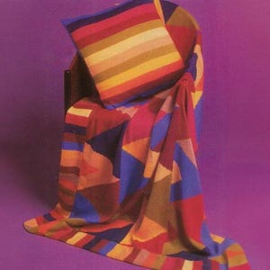 May include: A colorful geometric patterned throw blanket and pillow set. The blanket and pillow feature a mix of red, blue, orange, and yellow geometric shapes. The pillow has horizontal stripes of various colors.