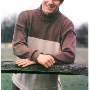 Peut inclure: Un jeune homme portant un pull marron et beige à col roulé, souriant et s'appuyant sur une clôture en bois.