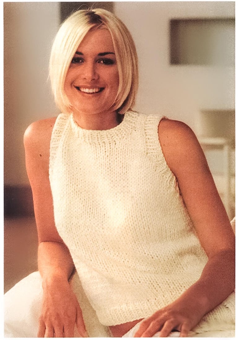 May include: A white sleeveless knitted top with a high neckline. The top is made of a soft, textured yarn.