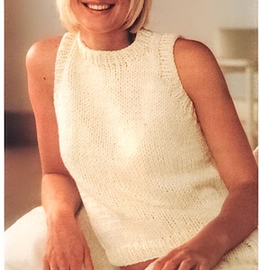 Puede incluir: Un top de punto sin mangas de color crema. El top tiene un cuello alto y un estilo ajustado.