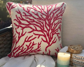 Può includere: Un cuscino quadrato con un vivace motivo a ramo di corallo rosso ricamato su una base in tessuto color crema. Il design copre l'intera superficie anteriore del cuscino, mostrando intricati dettagli di ramificazione in una tonalità rossa.