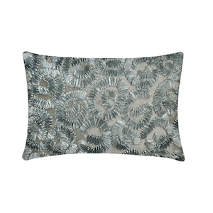 May include: A rectangular throw cushion featuring a light beige fabric base adorned with a dense pattern of metallic silver ribbon swirls. The ribbons are arranged in circular, ruffled formations that create a textured, three-dimensional surface.