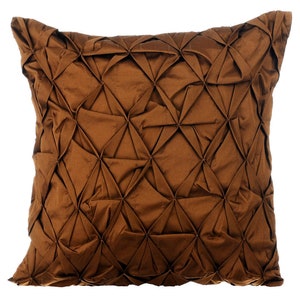 May include: A brown decorative pillow with a diamond-shaped pattern. The pillow is made of a soft, textured fabric.