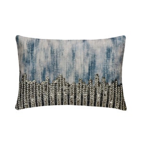 May include: A rectangular throw pillow with a blue and white ombre design. The bottom edge of the pillow is decorated with a silver beaded trim.