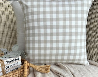May include: A square throw pillow featuring a beige and white gingham check pattern. The pillow is positioned in front of a stack of three white books with the words Thankful, Grateful, and Blessed printed on their spines in black text.