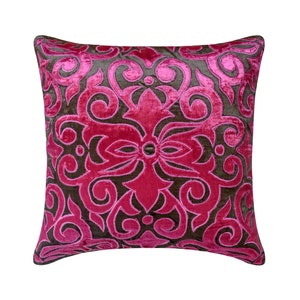May include: A pink velvet cushion with a brown embroidered floral design. The cushion is square and has a decorative border.