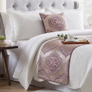 Peut inclure: Un ensemble de couvre-lit matelassé blanc comprenant un chemin de lit et un coussin carré, tous deux ornés d'un motif damassé mauve et violet. La literie est disposée sur un lit avec une tête de lit capitonnée gris clair et un plateau en bois.