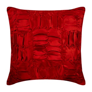 Pode incluir: Travesseiro decorativo vermelho com um design acolchoado e franzido. O travesseiro é feito de um tecido macio e luxuoso.