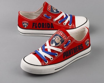 May include: Red canvas low-top sneakers with white laces and a blue accent. The shoes feature a Florida Panthers logo with the team name and "Florida" printed on the side.