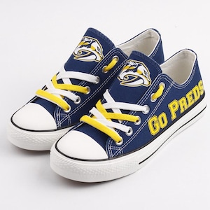 May include: A pair of blue canvas sneakers with yellow laces and a yellow logo on the side. The right shoe has the words "GO PREDS" printed on the side.